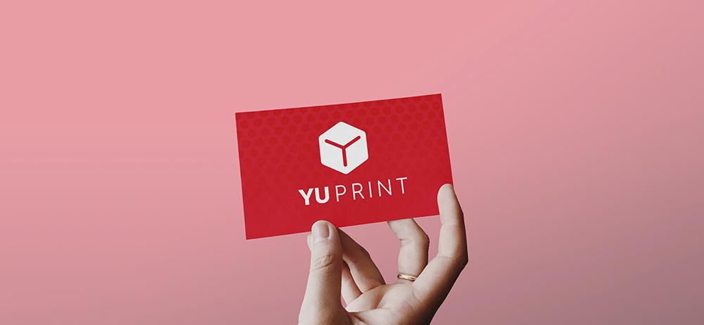 Tarjeta de presentación de Yuprint sostenida con la mano, diseño corporativo rojo con logotipo impreso.