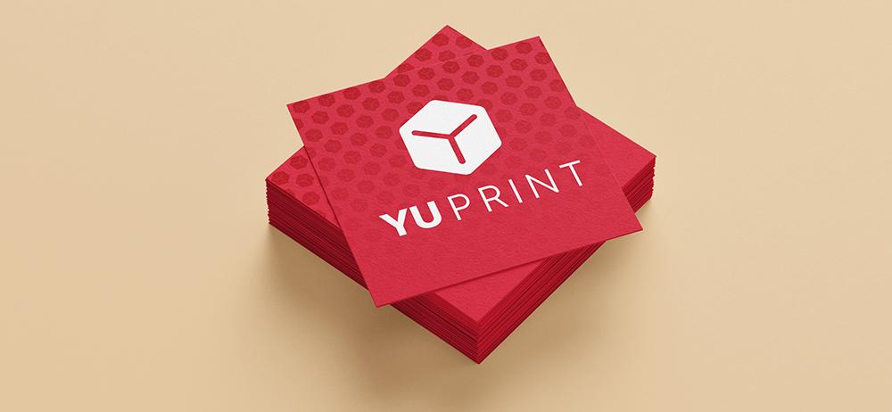 Stack de tarjetas cuadradas rojas con logotipo de Yuprint y fondo beige.