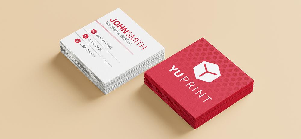Tarjetas cuadradas blancas y rojas con diseño corporativo de Yuprint sobre fondo beige.